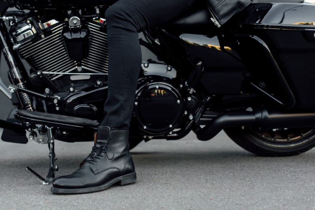 cropped view of man in black boot sitting on motorcycle